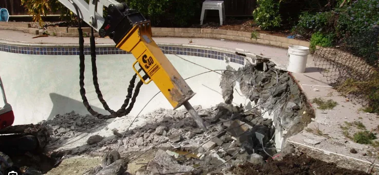 Concrete swimming pool shell being broken out during demolition
