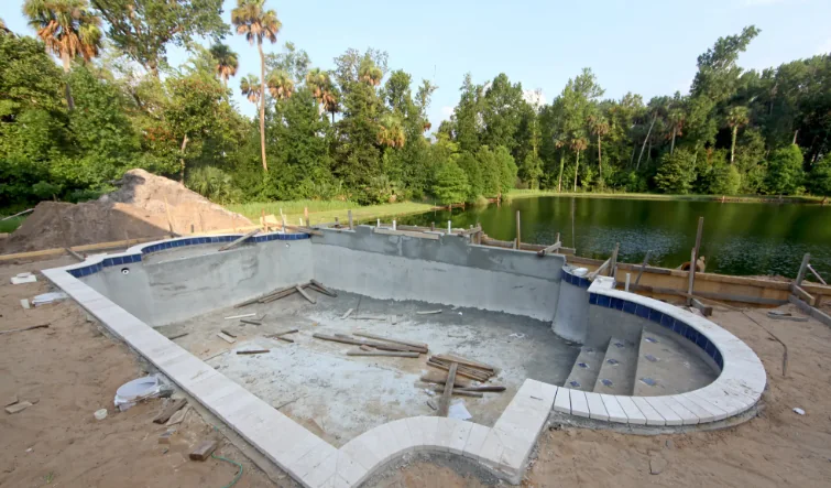 Empty residential swimming pool shell in an open backyard setting